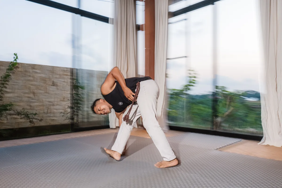 Capoeira teacher moving through a flowing grounded position in the shala